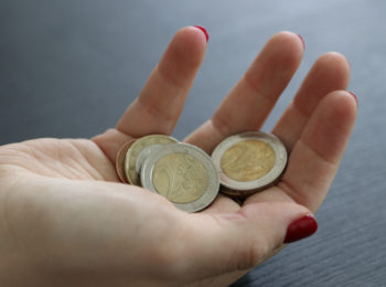 Weibliche Hand hält Euro-Münzen.